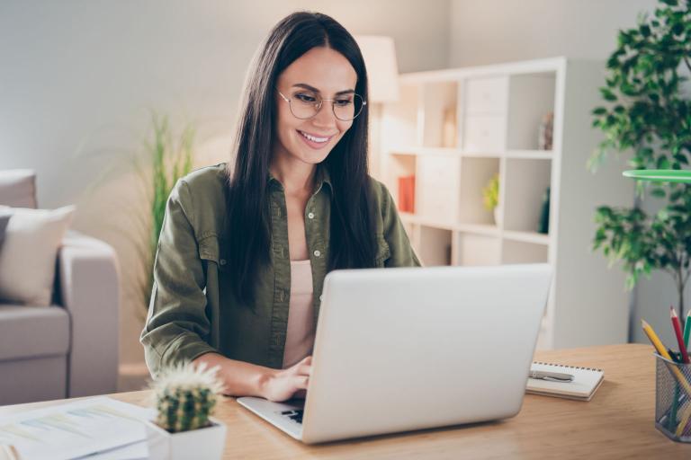 A young woman with glasses looking at a laptop. 