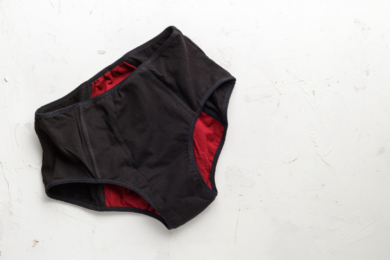 A pair of black and red coloured menstrual pants on a white background. 