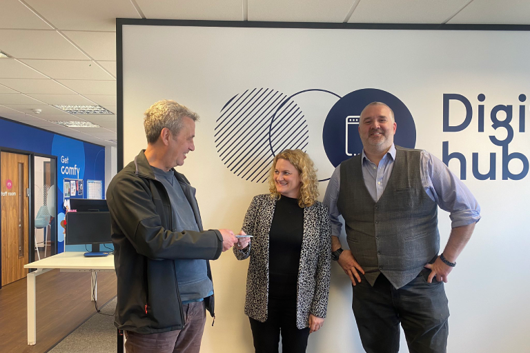 A group photograph of Councillor Louise McKinlay, Deputy Leader of Essex County Council and Cabinet Member for Community, Equality, Partnerships and Performance, giving resident Neil Davey a pre-loaded SIM card, pictured with Steve Woodman, Operations Manager for Reed in Partnership’s Restart Scheme in Colchester.