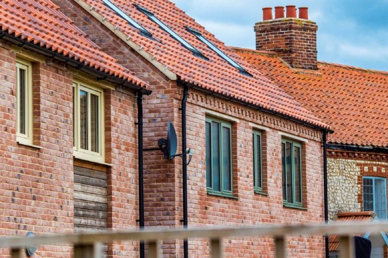 A row of brick houses, with green and yellow windows and solar panels on one of the roofs.