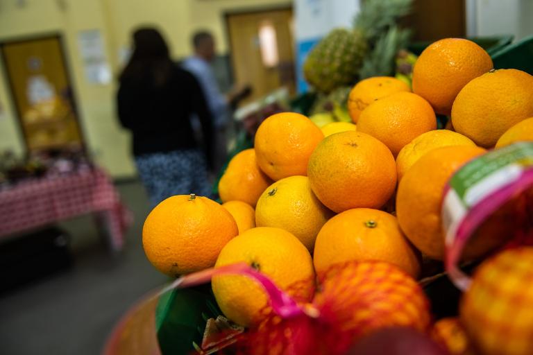 A close up photo of a collection of fresh satsumas on the shelf of a community supermarket.