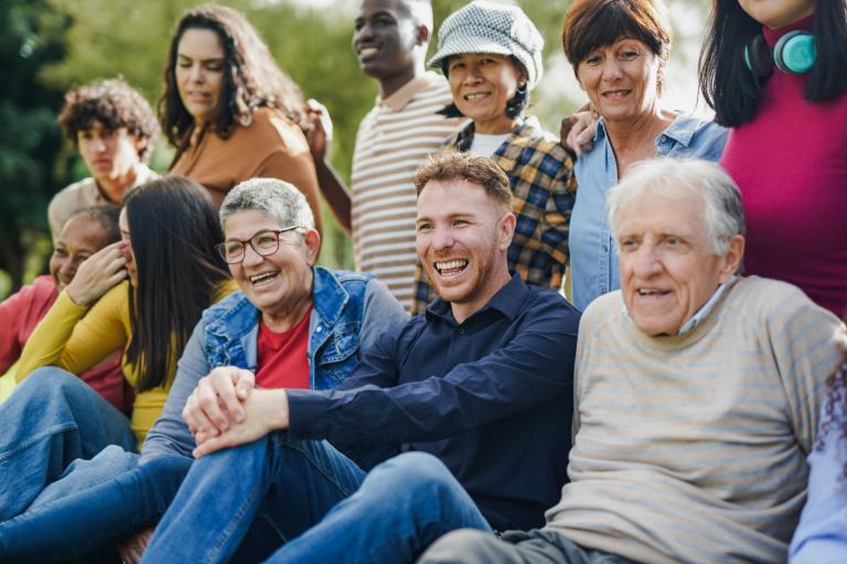 A cross generation group of people gathered together, some sitting and some standing, for a photograph 