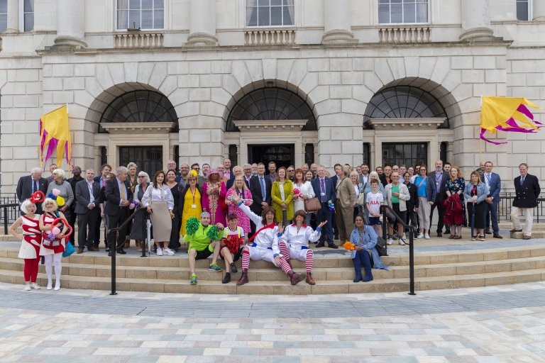 A large group of people in a group at the opening of Tindal Square. Some are stressed in colourful outfits.