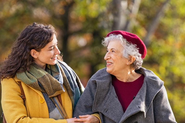 Two women linked arms smiling at each other 