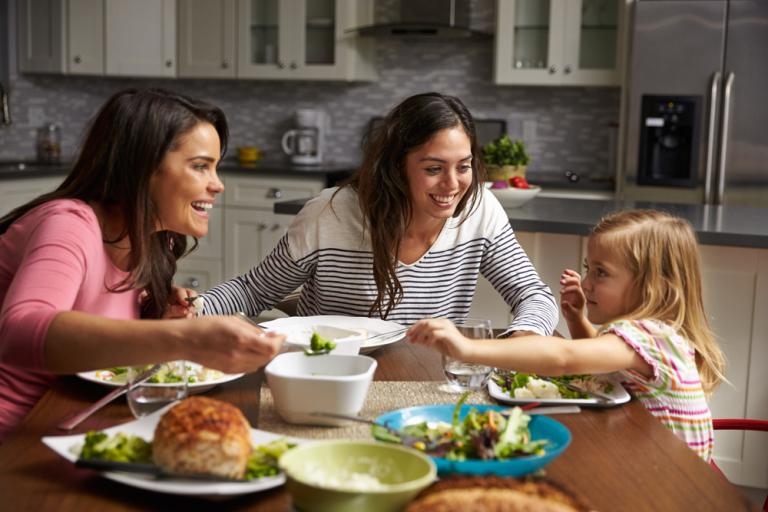 Two woman at a dinner table with a young child