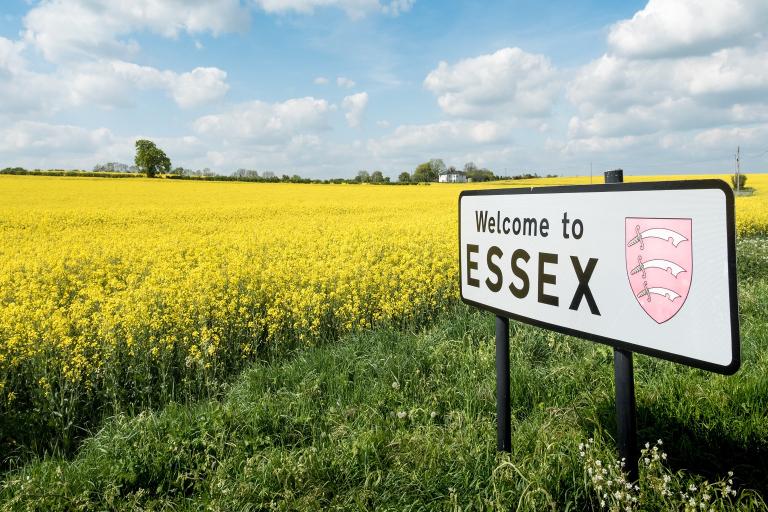 A rural English countryside scene on a bright spring day with a sign welcoming travellers to the English county of Essex.