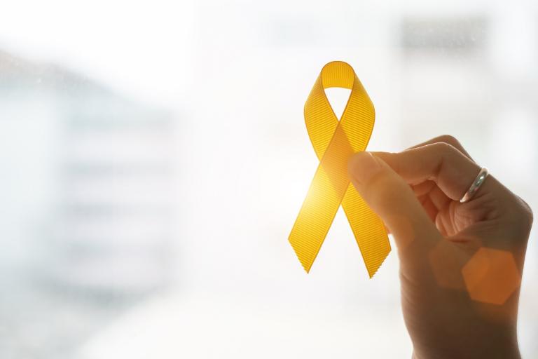 A hand holds up a yellow ribbon to mark World Suicide Prevention Day.