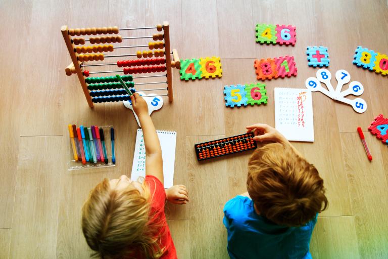 Two children on the floor learning numbers with an abacus