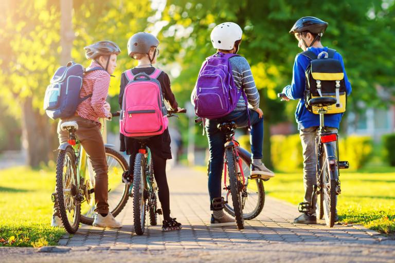 Four children wearing cycle helmets with their bikes, standing in a wooded area.