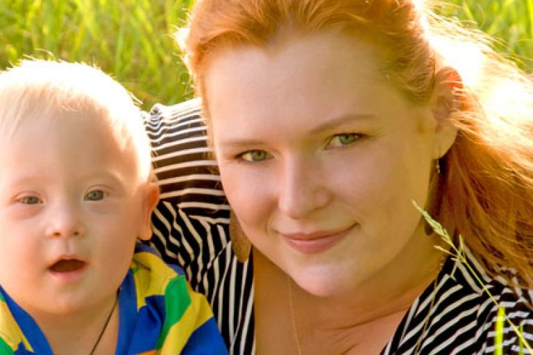smiling lady with child sitting on grass