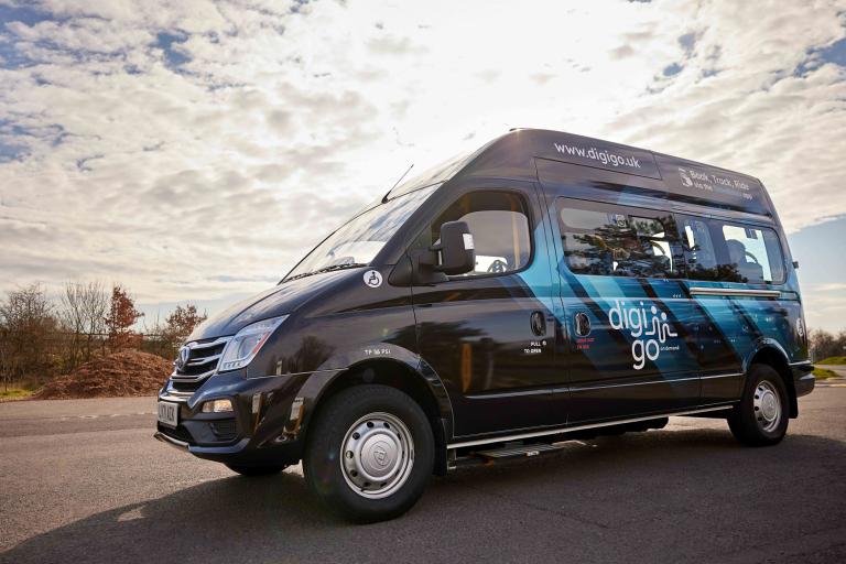 Branded DigiGo minibus turned to camera with cloudy skies and clear road in background.