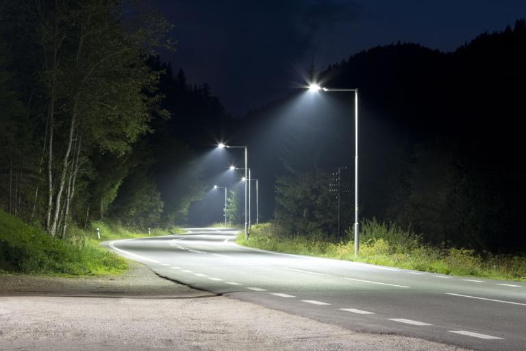 A road at night, with a row of streetlights lit up along it.