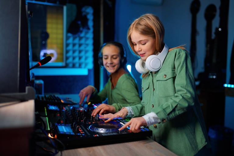 Two children using a sound mixer in radio station.