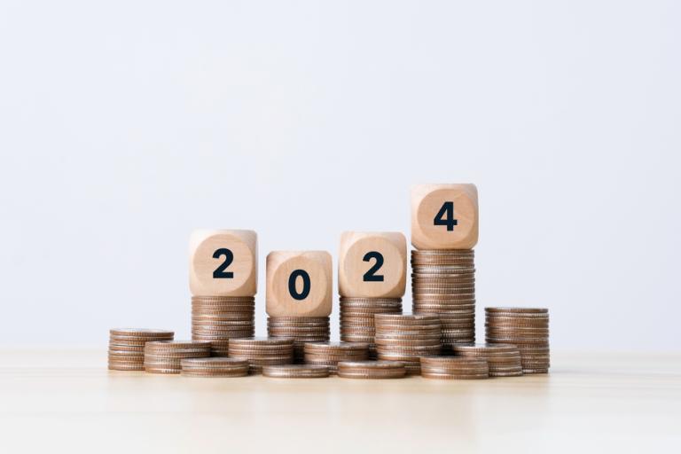 Wooden cubes reading 2024 atop stacks of pennies.