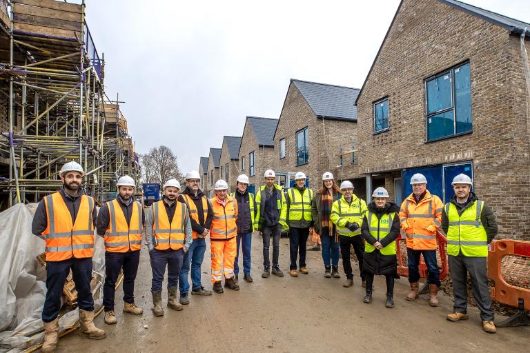 A large groups of people standing on a building site wearing hard hats and high-visibility jackets.