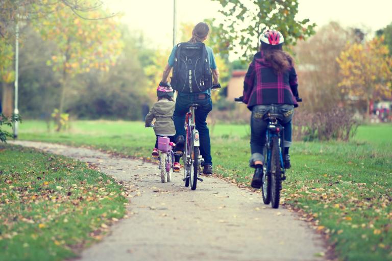 A man and woman cycling with their child through a park.
