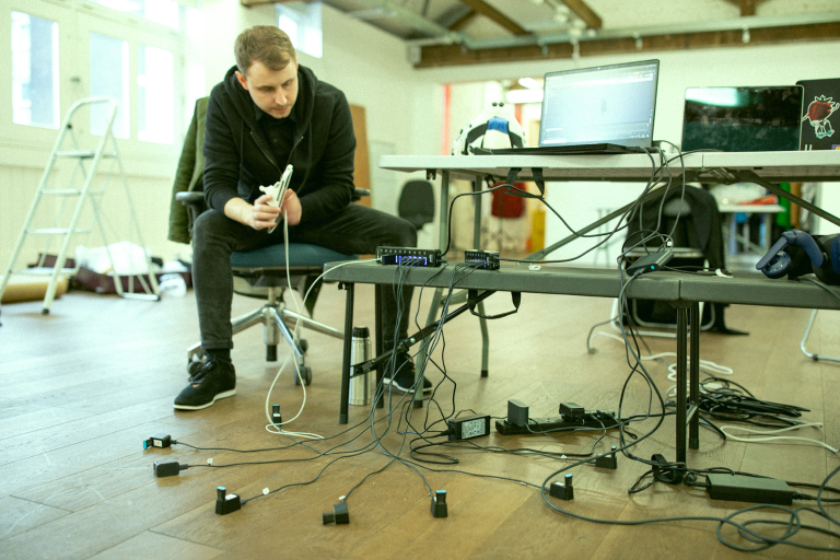 Man sat and hunched over while fiddling with wired technology.