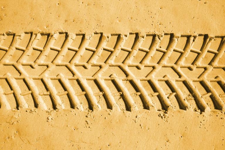 A picture of a set of heavy tyre tracks made in a sandy beach. 