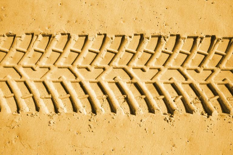 A picture of a set of heavy tyre tracks made in a sandy beach.