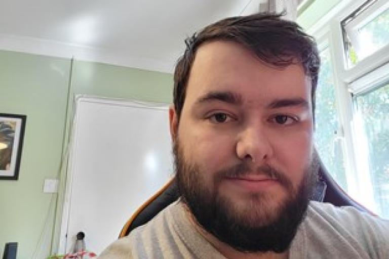 A man with a dark brown beard in a bright room