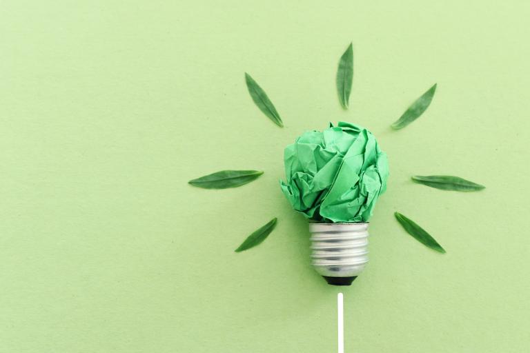 Illustration of a light bulb comprised of crumpled green paper to represent recycling.