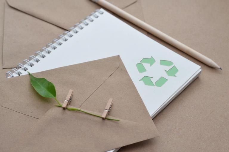 Eco-friendly notepad with recycling logo and pencils.