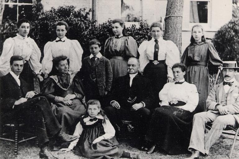1800s sepia of a family in formal wear posing for a photograph.