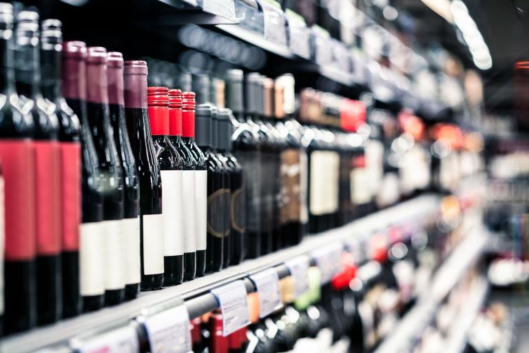 A large collection of wine bottles lined up on a shelf inside a shop.