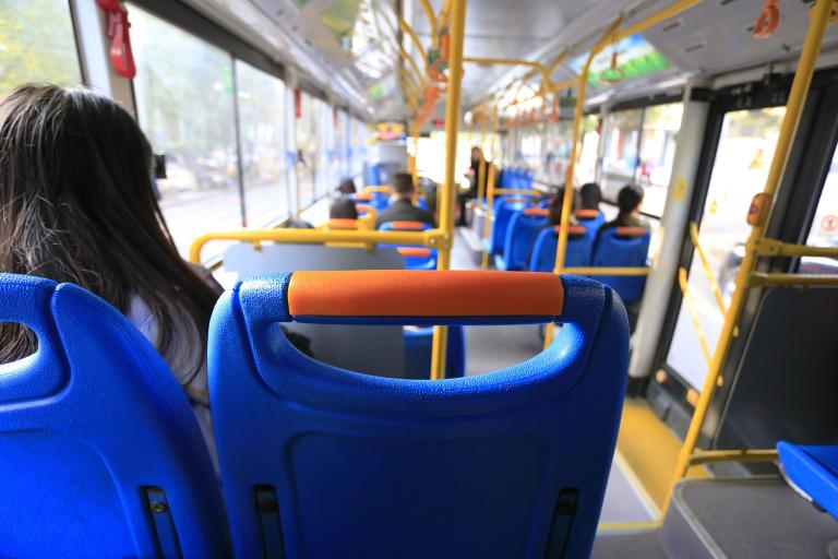 The inside of a bus showing a number of people sitting in seats from behind. 