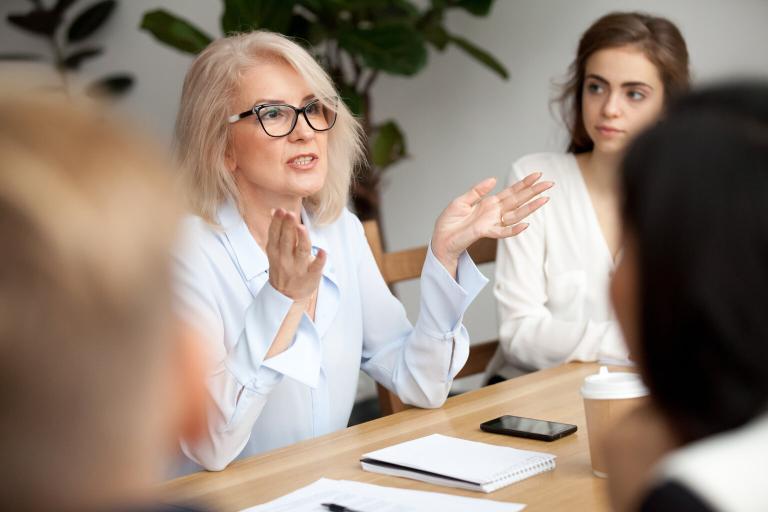 A blonde woman talking in a meetin