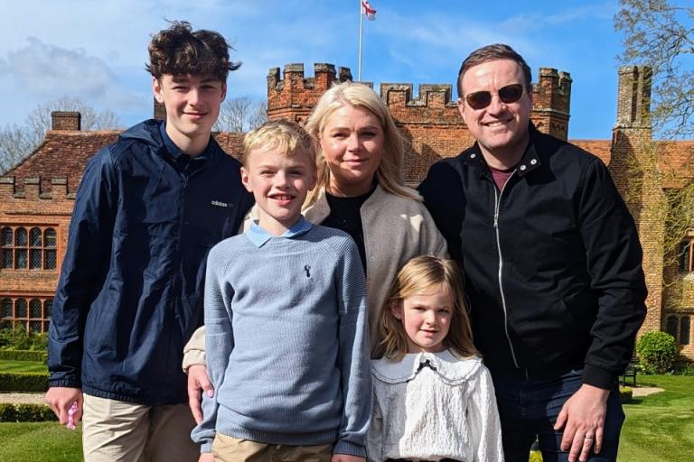 Two adults and three children looking happy in a park