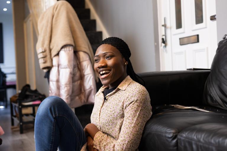 Laura, a foster carer, sitting on the floor with a smiling facial expression.