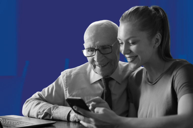older man and younger woman on mobile in front of laptop