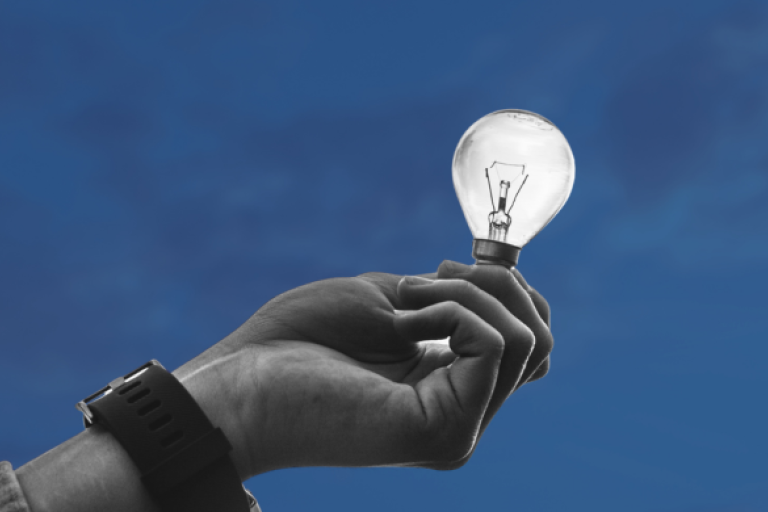hand holding a light bulb on blue background