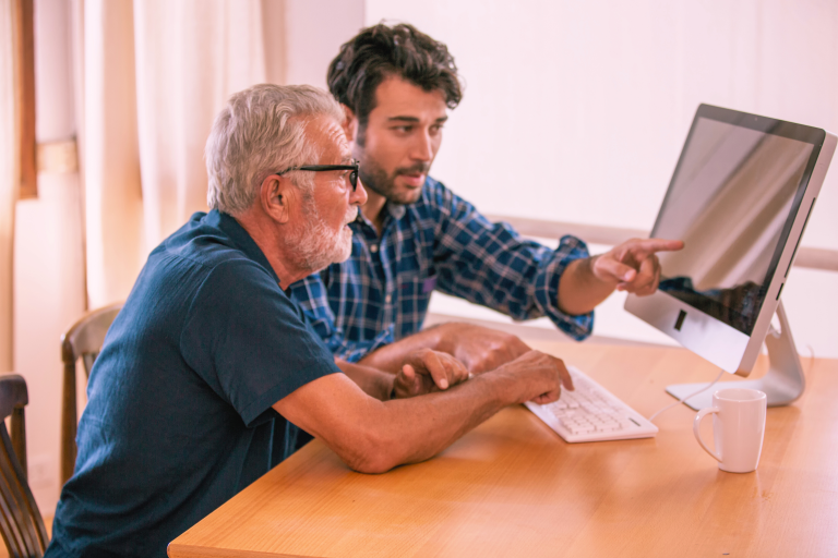 younger man showing older man how to use a computer