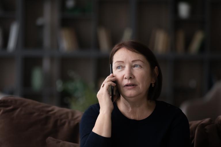 Headshot of a concerned woman on the phone looking into the distance.