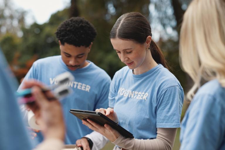 A group of men and women stand together wearing blue t-shirts with the word volunteer on them.