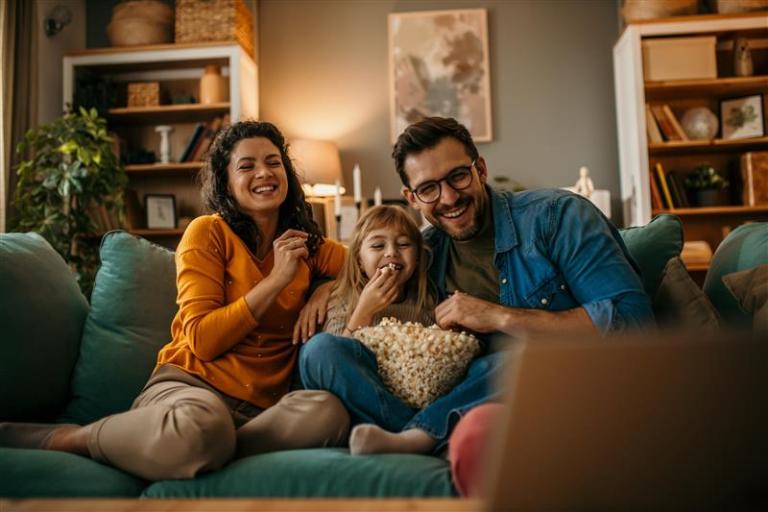 Family smiling on sofa eating popcorn