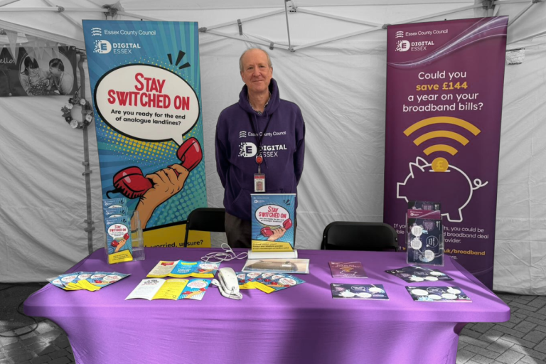 Person standing behind a promo table at an event for Digital Essex