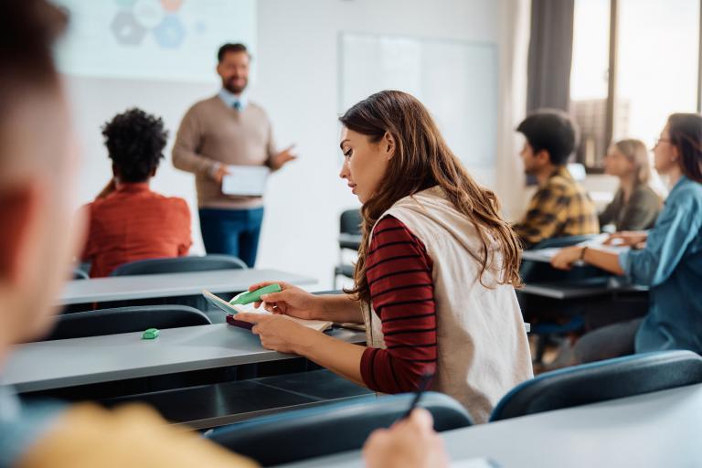 Young woman learning in classroom environment with back to camera