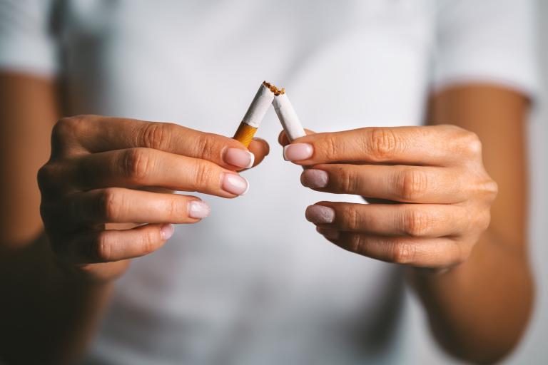 A woman holding a cigarette which has been snapped in half.