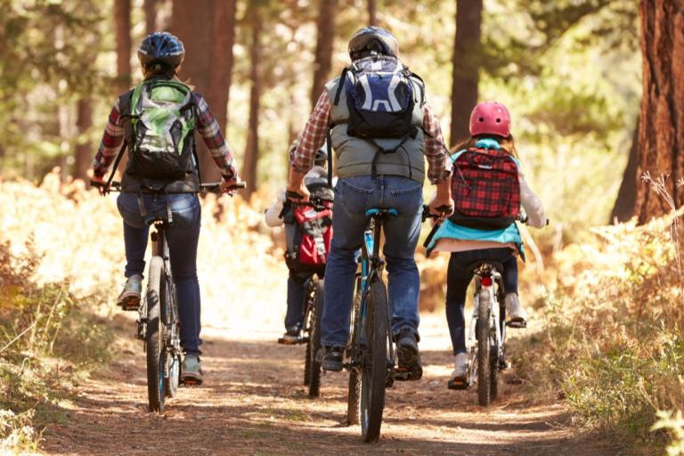 Parents and two children cycling through some woods