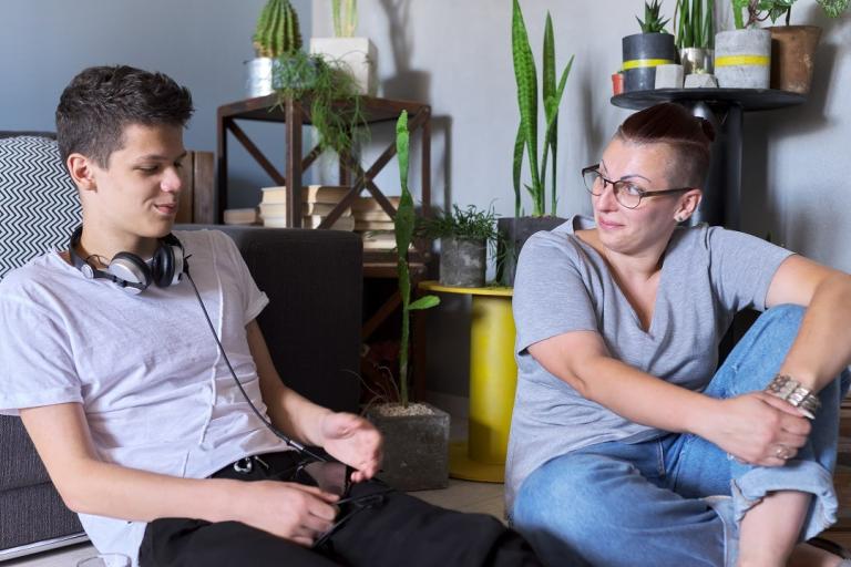 A teenage boy sitting on the floor with a psychologist.