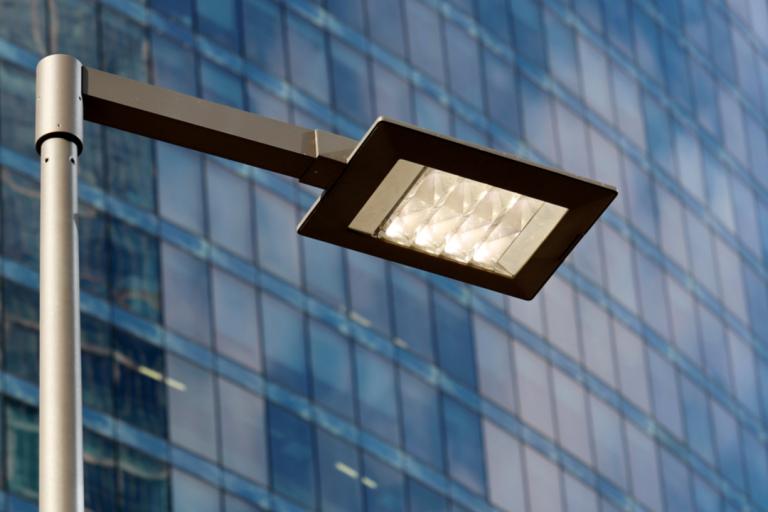 A photograph of an LED streetlight near a high rise building.