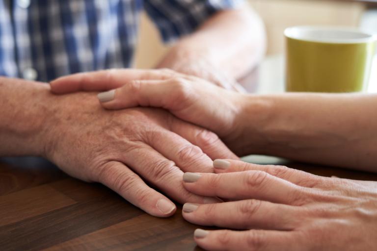 A close up of a woman's hands on top of an elderly man's hand.