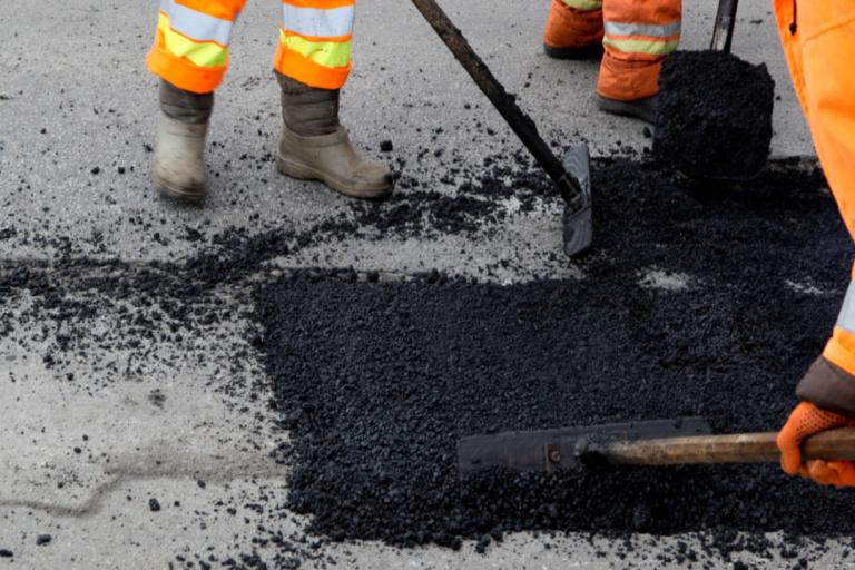 Workers spreading tarmac on a road