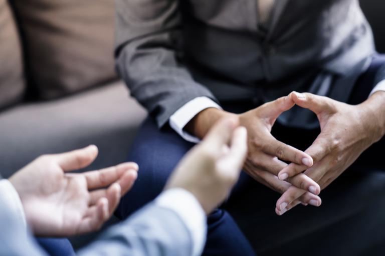 Two men engaged in a discussion, the photo is focused on their hands.