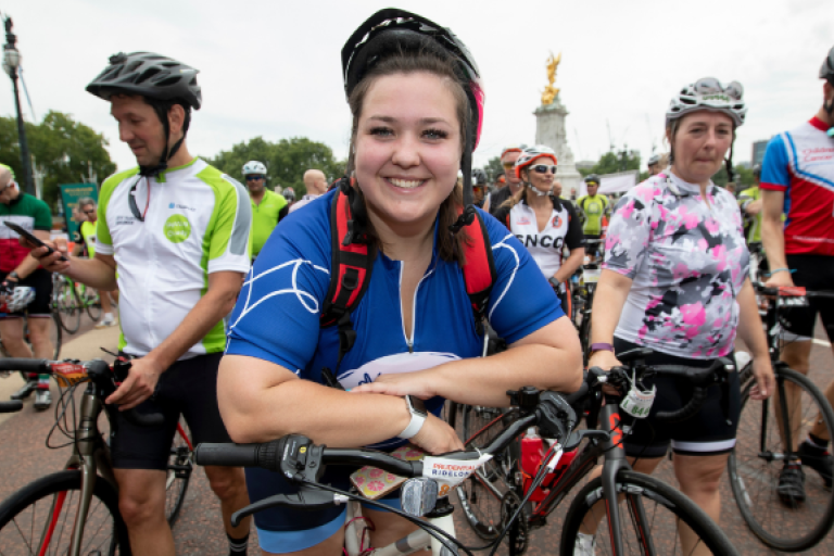 A lady leaning on a bike and smiling.